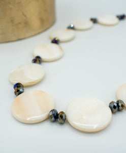 closeup of necklace with round pearl and glass beads with a gold plated closure