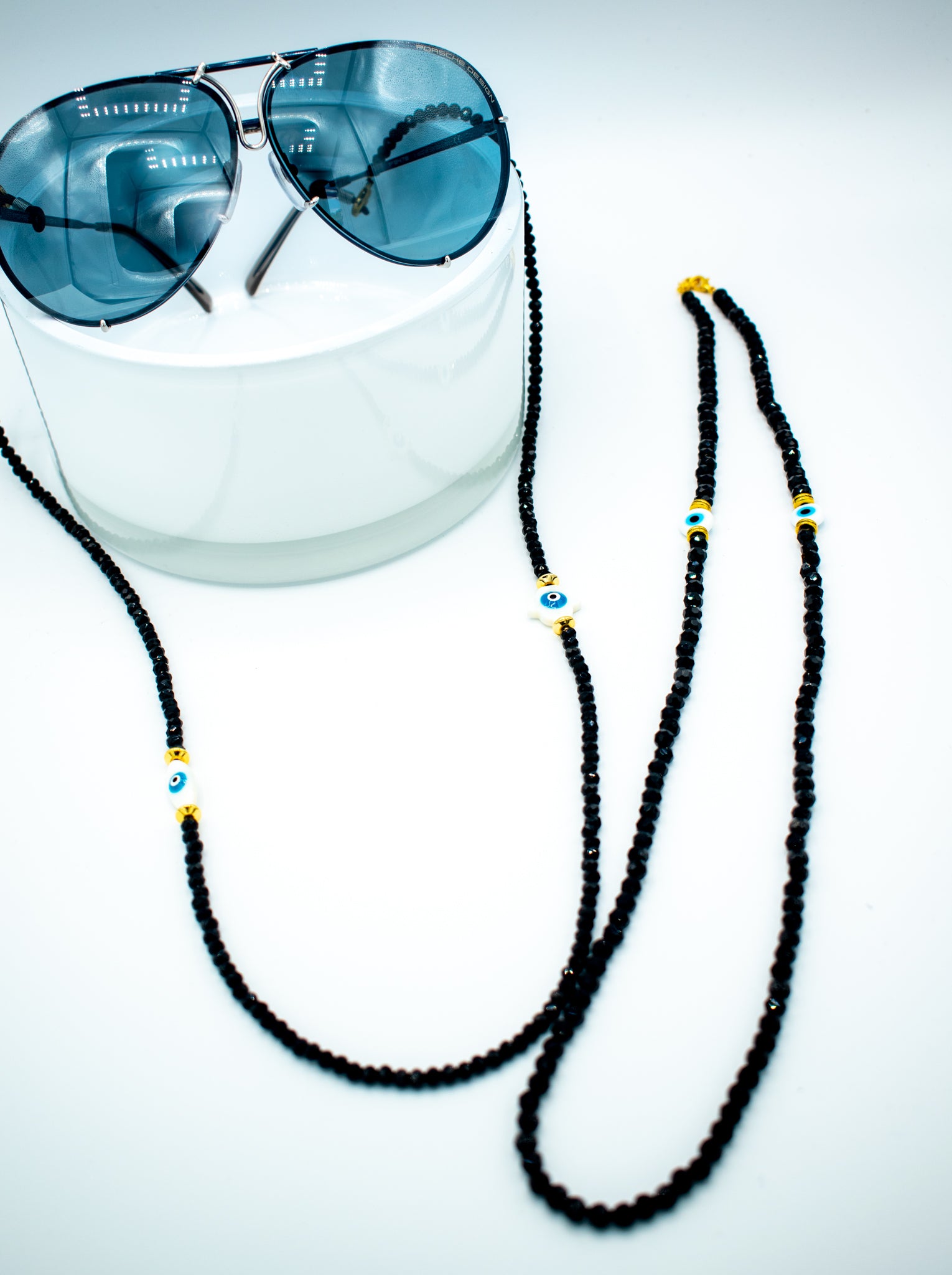 3 in 1 long beaded string black beads and evil eye bead with golden accent hooked on sunglasses