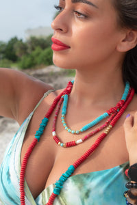 woman wearing a red bead necklace with lagoon blue, gold colored and white beads