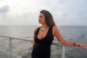 woman on a boat and wearing a Green crown healing necklace